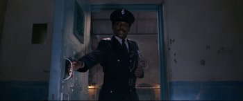 Movie still from “Paddington 2” (2017), directed by Paul King – A man in a police uniform holding a gun in his hand; Medium shot, Low angle