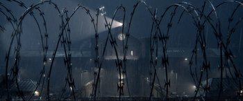 Movie still from “Paddington 2” (2017), directed by Paul King – A view of a clock tower through barbed wire; Extreme Wide shot, High angle
