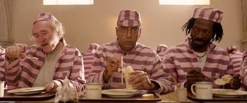 Movie still from “Paddington 2” (2017), directed by Paul King – A man in pink and white striped pajamas eating noodles; Medium shot, Low angle