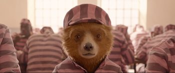 Movie still from “Paddington 2” (2017), directed by Paul King – A brown teddy bear wearing a pink and white striped shirt and hat; Close Up shot, Low angle
