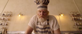Movie still from “Paddington 2” (2017), directed by Paul King – An old man with a beard wearing an apron and a chef's hat; Close Up shot, Low angle