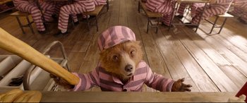 Movie still from “Paddington 2” (2017), directed by Paul King – A brown bear wearing a pink and gray striped pajamas; Medium shot, Overhead angle
