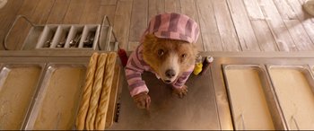 Movie still from “Paddington 2” (2017), directed by Paul King – A dog wearing a pink and white striped pajamas; Close Up shot, Overhead angle