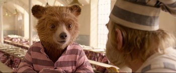 Movie still from “Paddington 2” (2017), directed by Paul King – A teddy bear is being held up by a man; Close Up shot, Over the shoulder angle