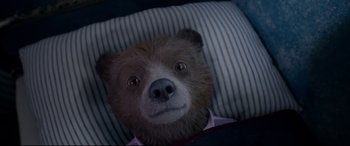 Movie still from “Paddington 2” (2017), directed by Paul King – A teddy bear is laying on a pillow; Close Up shot, Overhead angle