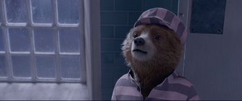 Movie still from “Paddington 2” (2017), directed by Paul King – A brown bear wearing a pink and white striped shirt and a hat; Close Up shot, High angle
