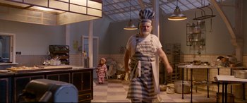 Movie still from “Paddington 2” (2017), directed by Paul King – An old man in a chef's outfit walking in a kitchen; Wide shot, Low angle