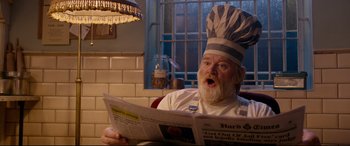 Movie still from “Paddington 2” (2017), directed by Paul King – A man in a chef's hat reading a newspaper; Close Up shot, Low angle
