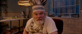 Movie still from “Paddington 2” (2017), directed by Paul King – An old man wearing a chef's hat with a surprised look on his face; Close Up shot, Low angle