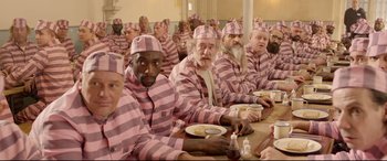 Movie still from “Paddington 2” (2017), directed by Paul King – A group of men sitting at a dinner table wearing pink and white striped pajamas; Medium shot, High angle