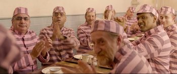 Movie still from “Paddington 2” (2017), directed by Paul King – A group of men in pink and white prison uniforms; Medium shot, Over the shoulder angle