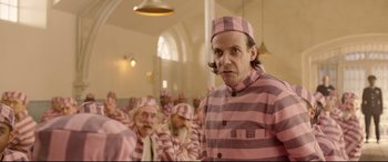 Movie still from “Paddington 2” (2017), directed by Paul King – A group of men in pink and black striped pajamas; Medium shot, Over the shoulder angle