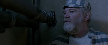 Movie still from “Paddington 2” (2017), directed by Paul King – An old man with a beard and a hat is looking at a pipe; Close Up shot, Overhead angle