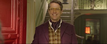Movie still from “Paddington 2” (2017), directed by Paul King – A man in a purple jacket and a plaid shirt smiling for the camera; Medium shot, Low angle