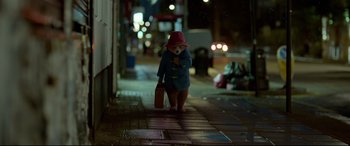 Movie still from “Paddington 2” (2017), directed by Paul King – A person with a red hat is walking down the street; Wide shot, Low angle
