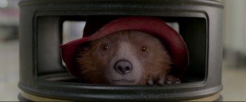 Movie still from “Paddington 2” (2017), directed by Paul King – A brown teddy bear wearing a red hat; Close Up shot, Overhead angle