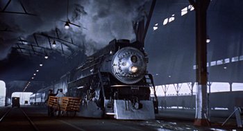 Movie still from “Pal Joey” (1957), directed by George Sidney – An old steam engine train in a train station; Extreme Wide shot, Low angle
