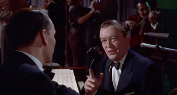 Movie still from “Pal Joey” (1957), directed by George Sidney – A man wearing a suit and tie talking to another man in a suit and tie; Close Up shot, Over the shoulder angle
