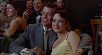 Movie still from “Pal Joey” (1957), directed by George Sidney – A man and a woman sitting next to each other in front of other people; Medium shot, Low angle