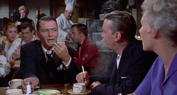 Movie still from “Pal Joey” (1957), directed by George Sidney – Two men sitting at a table in front of a stove; Medium shot, Over the shoulder angle