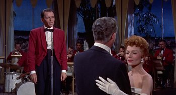 Movie still from “Pal Joey” (1957), directed by George Sidney – A man and a woman in front of an audience; Medium shot, Over the shoulder angle