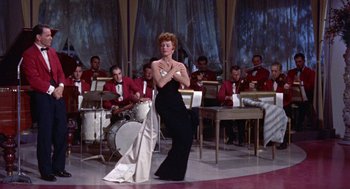 Movie still from “Pal Joey” (1957), directed by George Sidney – A woman in a black dress is in front of an orchestra; Wide shot, Low angle