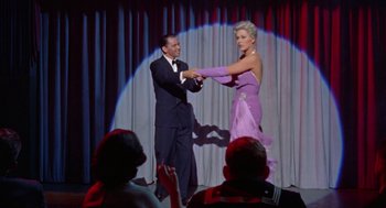 Movie still from “Pal Joey” (1957), directed by George Sidney – A man and a woman dancing on a stage in front of an audience; Wide shot, Low angle
