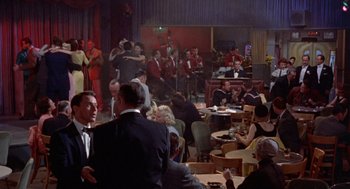 Movie still from “Pal Joey” (1957), directed by George Sidney – A group of people sitting at tables in a room; Wide shot, High angle
