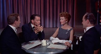 Movie still from “Pal Joey” (1957), directed by George Sidney – An older man and woman sitting at a table in a restaurant; Medium shot, Over the shoulder angle