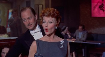 Movie still from “Pal Joey” (1957), directed by George Sidney – A woman in a blue dress and a man in a black suit; Medium shot, Low angle