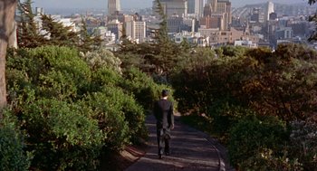 Movie still from “Pal Joey” (1957), directed by George Sidney – A man walking down a path in the middle of a city; Extreme Wide shot, High angle