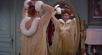 Movie still from “Pal Joey” (1957), directed by George Sidney – A woman is standing in front of a mirror; Medium shot, Over the shoulder angle