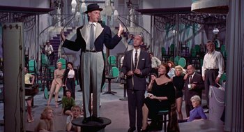 Movie still from “Pal Joey” (1957), directed by George Sidney – A group of people sitting and standing in a room; Wide shot, Low angle