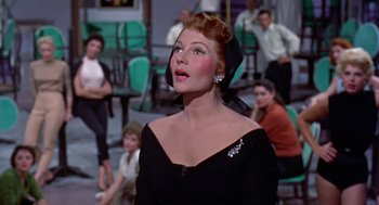 Movie still from “Pal Joey” (1957), directed by George Sidney – A woman wearing a black dress and a black hat; Medium shot, Low angle