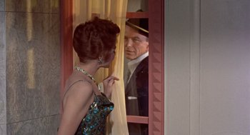 Movie still from “Pal Joey” (1957), directed by George Sidney – A woman standing in front of an open window looking at an older man; Medium shot, Over the shoulder angle