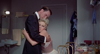 Movie still from “Pal Joey” (1957), directed by George Sidney – A man and a woman hugging in a room; Medium shot, High angle