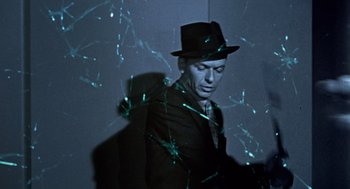 Movie still from “Pal Joey” (1957), directed by George Sidney – A man wearing a hat standing in front of broken glass; Close Up shot, Low angle