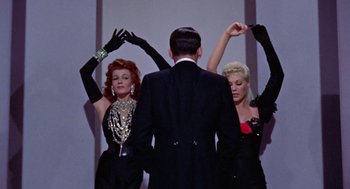 Movie still from “Pal Joey” (1957), directed by George Sidney – A man and two women are dancing together; Medium shot, Low angle