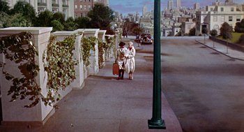 Movie still from “Pal Joey” (1957), directed by George Sidney – A painting of two people walking down a sidewalk; Extreme Wide shot, High angle
