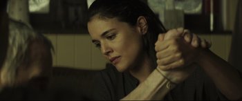 Movie still from “Palm Trees in the Snow” (2015), directed by Fernando González Molina – A young woman holding her arm around her wrist; Close Up shot, Low angle