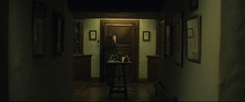 Movie still from “Palm Trees in the Snow” (2015), directed by Fernando González Molina – A woman standing in front of an open door in a room; Wide shot, Low angle
