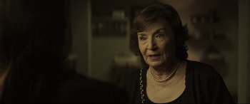 Movie still from “Palm Trees in the Snow” (2015), directed by Fernando González Molina – An older woman wearing a black top and pearl necklace; Close Up shot, Over the shoulder angle