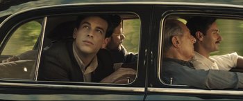 Movie still from “Palm Trees in the Snow” (2015), directed by Fernando González Molina – A man sitting in the passenger seat of a car; Medium shot, Low angle
