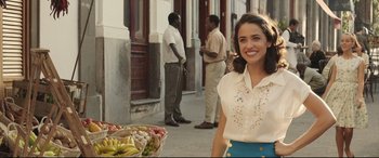 Movie still from “Palm Trees in the Snow” (2015), directed by Fernando González Molina – A woman standing in front of a basket of fruit; Medium shot, Over the shoulder angle