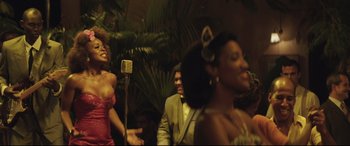 Movie still from “Palm Trees in the Snow” (2015), directed by Fernando González Molina – A group of people standing next to each other in front of a microphone; Medium shot, Over the shoulder angle