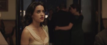 Movie still from “Palm Trees in the Snow” (2015), directed by Fernando González Molina – A woman standing in front of a group of people; Close Up shot, Over the shoulder angle