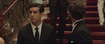 Movie still from “Palm Trees in the Snow” (2015), directed by Fernando González Molina – A man in a suit and tie standing next to another man in a suit and tie; Close Up shot, Over the shoulder angle