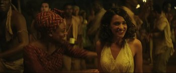 Movie still from “Palm Trees in the Snow” (2015), directed by Fernando González Molina – Two women are dancing together in front of a group of people; Medium shot, Over the shoulder angle