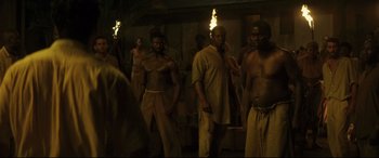 Movie still from “Palm Trees in the Snow” (2015), directed by Fernando González Molina – A group of men standing next to each other in a room; Medium shot, High angle