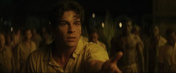 Movie still from “Palm Trees in the Snow” (2015), directed by Fernando González Molina – A man in a yellow shirt is looking at the camera; Close Up shot, Over the shoulder angle
